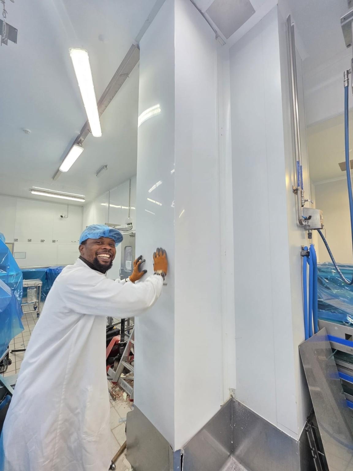 Operari instal·lant planxes P3 en una paret interior de zona de producció